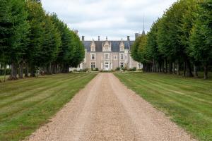 uma estrada de terra em frente a uma casa com árvores em Château de Beauvais em Azay-sur-Cher