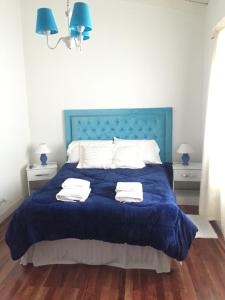1 dormitorio con 1 cama azul y 2 toallas en Dpto. Tribuno en Salta