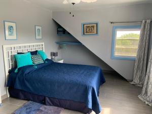 a bedroom with a blue bed and a staircase at Turtles Nest Bahamas in Hermitage
