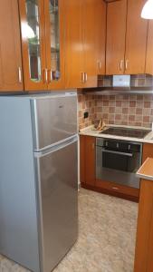uma cozinha com armários de madeira e um frigorífico de aço inoxidável em Roas Apartment Golem em Golem