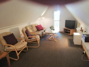 - un salon mansardé avec des chaises et une télévision dans l'établissement Gæstebolig,Tørresøvej 87, à Otterup