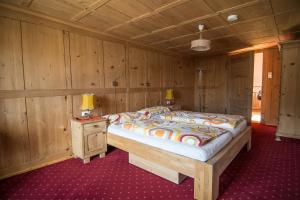 1 dormitorio con 1 cama y pared de madera en Ferienwohnung Sonnenhof, en Andelsbuch