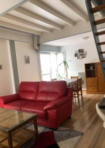 a living room with a red couch and a table at les magnolias in Colmar