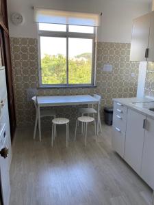 een keuken met een tafel en twee krukken voor een raam bij FAMILY APARTMENT LISBON-ESTORIL in Estoril