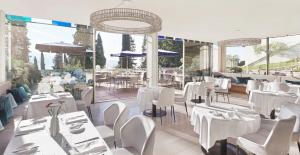 a restaurant with white tables and chairs and windows at Eden Reserve Hotel in Gardone Riviera
