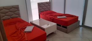 two beds in a room with red sheets and a mirror at eri apartament in Himare