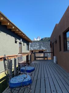 eine Holzterrasse mit 2 Stühlen und einem Tisch in der Unterkunft Guanaca Lodge in El Chalten