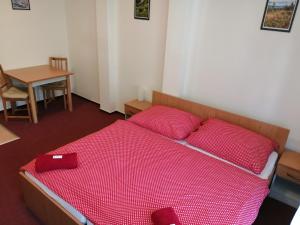 a bedroom with a bed with red sheets and a table at Apartmány pod vlekem in Horní Maršov