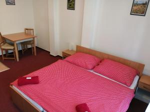ホルニー・マルショフにあるApartmány pod vlekemのベッドルーム1室(赤いシーツとテーブル付きのベッド1台付)