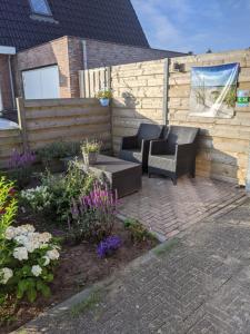 a patio with two chairs and a table and flowers at Logies21 Texel in Oosterend