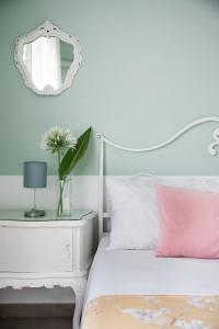 a white bed with a pink pillow and a mirror at Villa Ortensia in Aci Castello