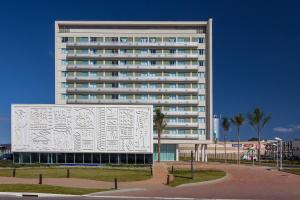 a large white building with a mural on the side of it at San Diego Suites Veredas Sete Lagoas in Sete Lagoas