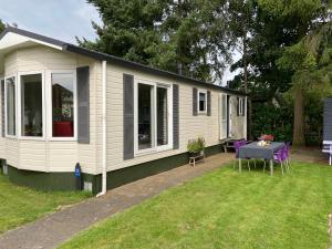 a tiny house with a table in the yard at Ruim en modern chalet in de Veluwse bossen in Putten