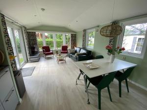 een woonkamer met een tafel en stoelen bij Ruim en modern chalet in de Veluwse bossen in Putten