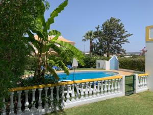 a white fence next to a swimming pool with a palm tree at Villa Roja Pé in Albufeira