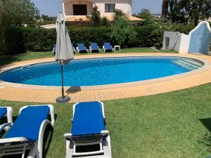 
a swimming pool with chairs and umbrellas at Villa Roja Pé in Albufeira
