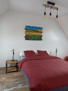 um quarto com uma cama vermelha e um quadro na parede em Le Repos du Randonneur em Audinghen