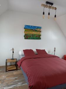 a bedroom with a red bed and a painting on the wall at Le Repos du Randonneur in Audinghen