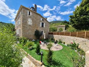 an old stone house with a garden in front of it at Le mas ROLLAND - Piscine & SPA - MILLAU-GORGES du TARN in Compeyre