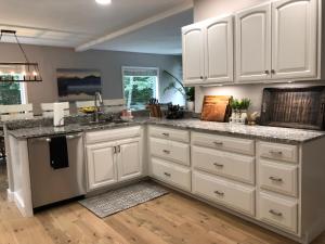 una cucina con armadi bianchi e ripiani in granito di The Mighty Oaks Retreat,modern house Bar Harbor Acadia MDI a Bar Harbor