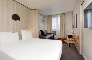 Cette chambre comprend un grand lit et une chaise. dans l'établissement Kyriad Clermont-Ferrand-Sud - La Pardieu, à Clermont-Ferrand