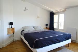 a bedroom with a bed with a blue comforter and a window at T3 cosy au centre de Castelnaudary in Castelnaudary