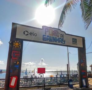 a sign on a beach with the ocean in the background at Suítes Cavalo Marinho in Porto De Galinhas