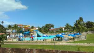 a large pool with a slide and blue umbrellas at Kitnet Clokel ap 104 A in Jacumã
