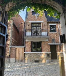 een bakstenen gebouw met een balkon in een bakstenen straat bij Le petit béguinage in Tongeren