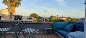 a blue couch on a deck with a table and chairs at Maison de vacances à l'Ayguade classée 3 étoiles, climatisée,3mn à pied plage et restos ,5mn aéroport, 10mn gare in Hyères