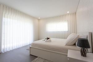 a bedroom with a white bed with a lamp and windows at Basto Village House - Eco Smart Luxury Villa in Cabeceiras de Basto +56 photos