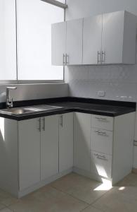 a kitchen with white cabinets and a black counter top at Departamento Mapy en Piura in Piura