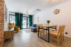 a dining room and living room with a table and chairs at Siedlisko Widzimy Się in Baligród