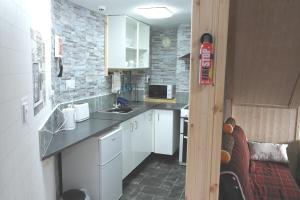 a small kitchen with white cabinets and a microwave at The Steading Country Self Catering in Drumnadrochit