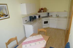 una cucina con armadi bianchi, tavolo e scatola di Müllers erste Ferienwohnung in der Altstadt von Görlitz a Görlitz