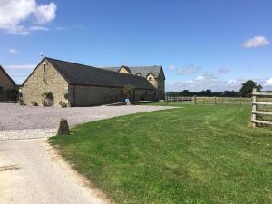 a barn with a grass field next to a fence at Whaddon Grove House in Melksham