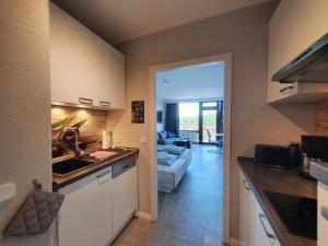 eine Küche mit einem Waschbecken und ein Wohnzimmer in der Unterkunft Harz Loft - Vier Jahreszeiten in Hahnenklee-Bockswiese