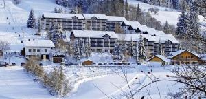 un complexe dans la neige avec des bâtiments recouverts de neige dans l'établissement Ferienwohnung AlpenGlück im Ferienpark Oberallgäu mit Hallenbad, Sauna, WLAN, à Missen-Wilhams