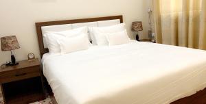 uma grande cama branca num quarto com 2 candeeiros em برج الأعمال em Qal'at Bishah