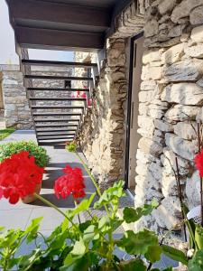 un muro di pietra e fiori rossi accanto a una porta di V&V RentRoom Design a Gignod