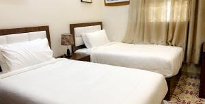2 camas en una habitación de hotel con sábanas blancas en برج الأعمال, en Qal'at Bishah