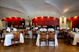 a dining room with white tables and chairs and red walls at Real de Minas Poliforum in León