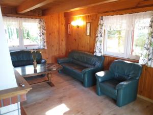 a living room with couches and a table and windows at Dom pod Sosnami in Narty