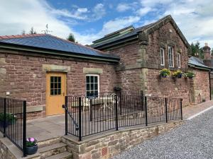 una casa de ladrillo con una valla delante de ella en Pumping Station Holidays en Cinderford