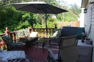 a patio with chairs and an umbrella on a deck at La Maison entre Mer Montagnes in Cap-Chat