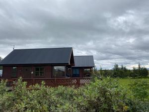 a wooden cabin with a black roof on a field at Borgarbæli in Hella
