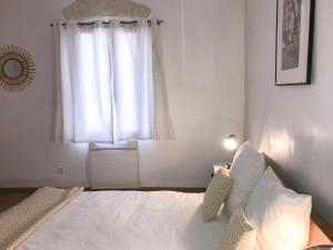 a bedroom with a white bed and a window at La Maison bleue in Arles