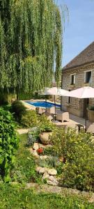 a garden with umbrellas and a swimming pool at Au fil de l’Ô in Bisseuil