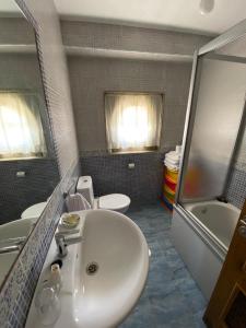 een badkamer met een wastafel, een bad en een toilet bij Casa El Hórreo in Laxe