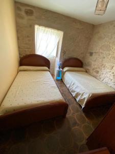 twee bedden in een kleine kamer met een raam bij Casa El Hórreo in Laxe